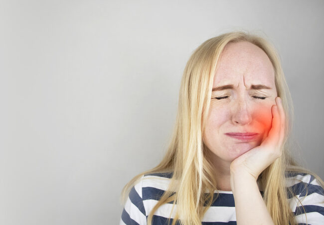 A Woman Clings To His Cheek And Winces In Pain In His Tooth. The