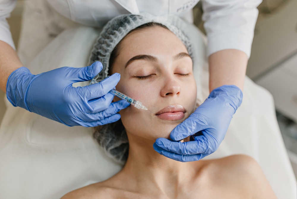 Portrait young woman during cosmetology procedures in beauty salon. Injecting, botox, hands in blue glows, healthcare, therapy, lips, beauty. Botox